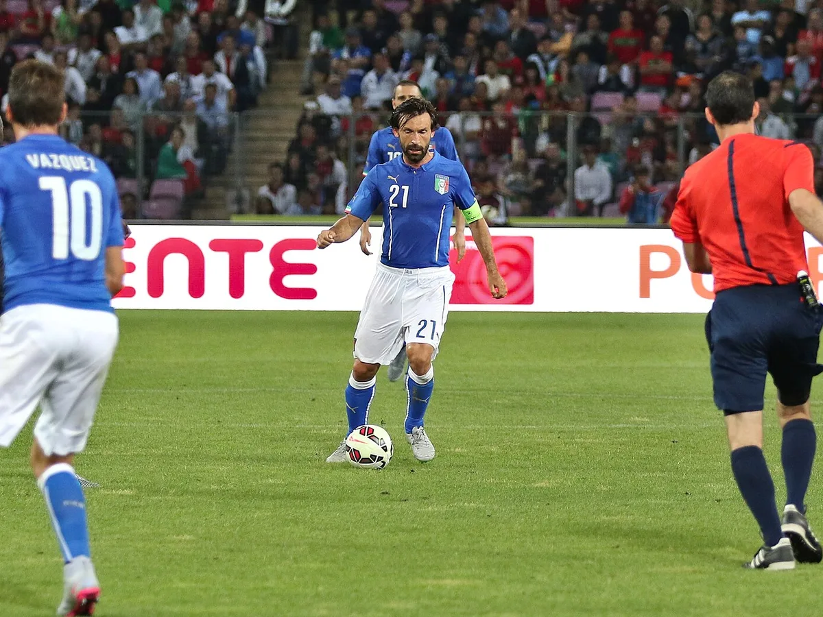 Andrea Pirlo med lagkaptensbindel och bollen vid foten i Italiens blå landslagströja under en landskamp 2015