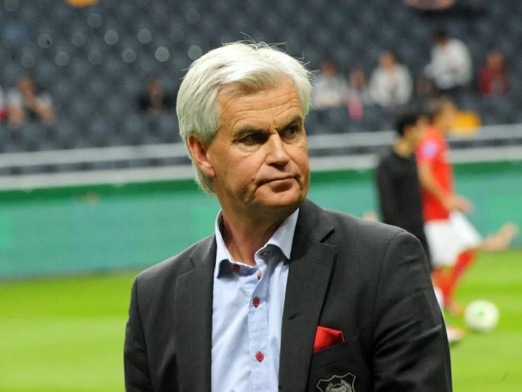 Nanne Bergstrand i kavaj vid sidlinjen på en fotbollsarena