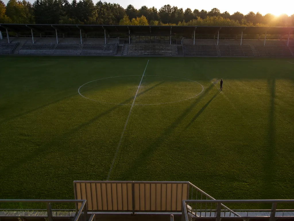 Domare håller upp ett gult kort mot en klarblå himmel på en fotbollsplan